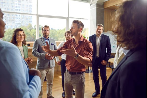 Gruppe von Mitarbeitenden im Workshop, eine Person spricht und moderiert den Austausch im Team